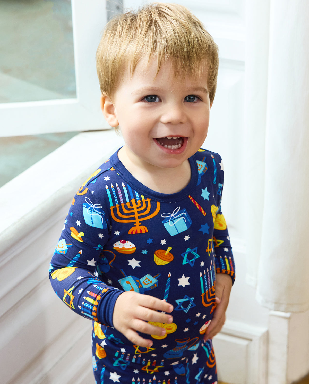Close front view of a smiling child in the Hanukkah Magic long-sleeve top.