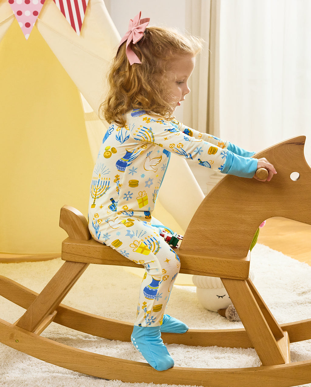 Rear view of a child holding a wooden rocking horse in the Happy Hanukkah romper.