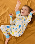 Child reclining on orange bedding with arms raised in the Happy Hanukkah two-piece set.