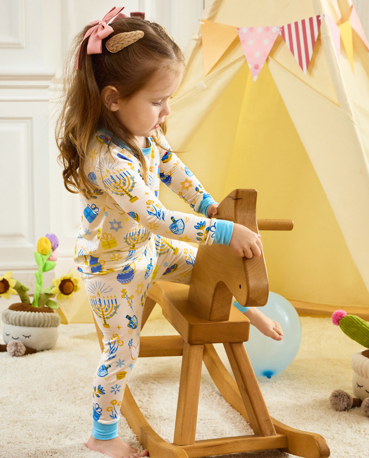 Side view of a child standing beside a wooden rocking horse in the Happy Hanukkah set.
