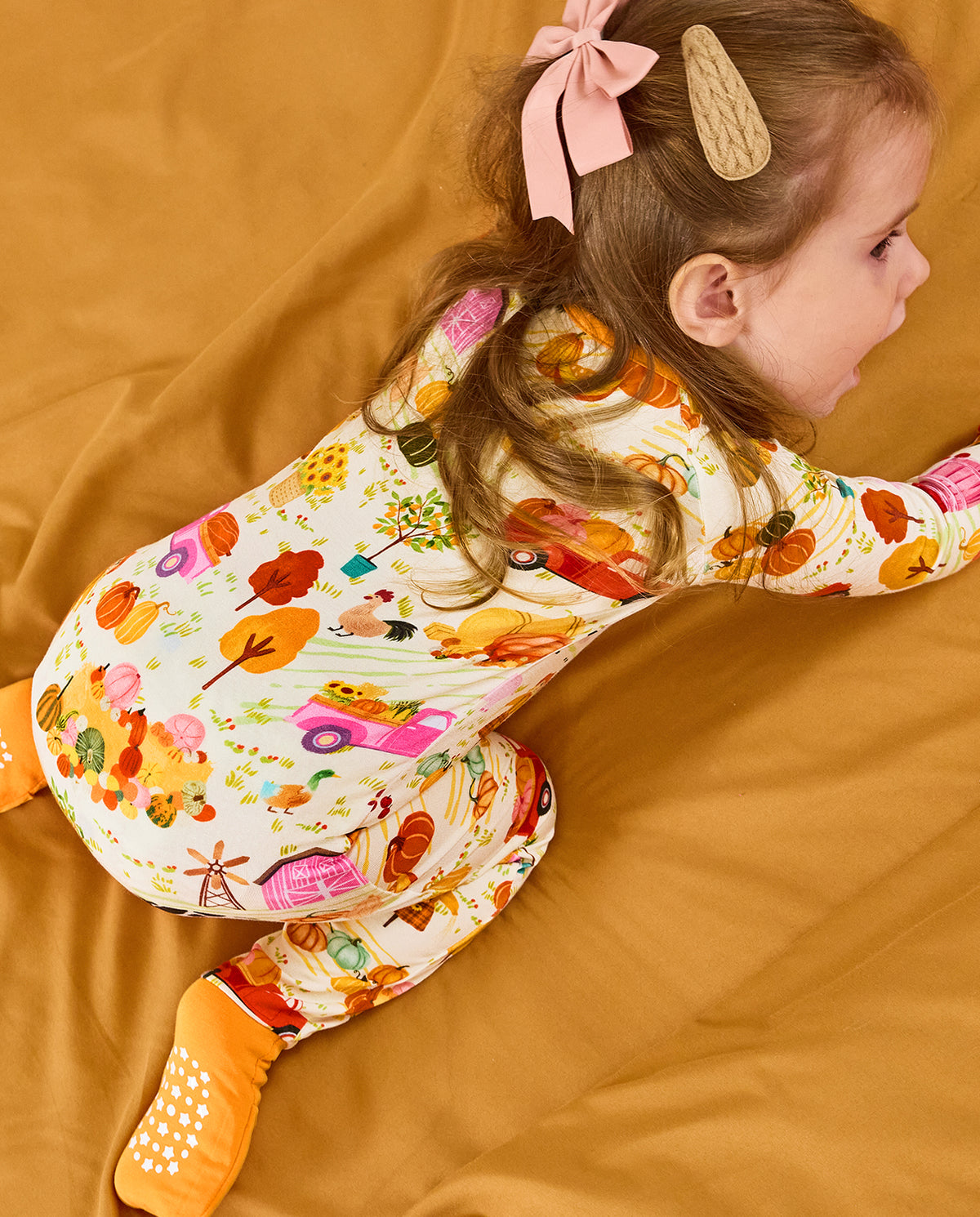 Rear shoulder view of a reclining child wearing the Harvest Farm romper.