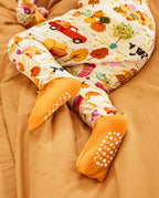Close-up of orange foot cuffs and white sole grips on the Harvest Farm romper.