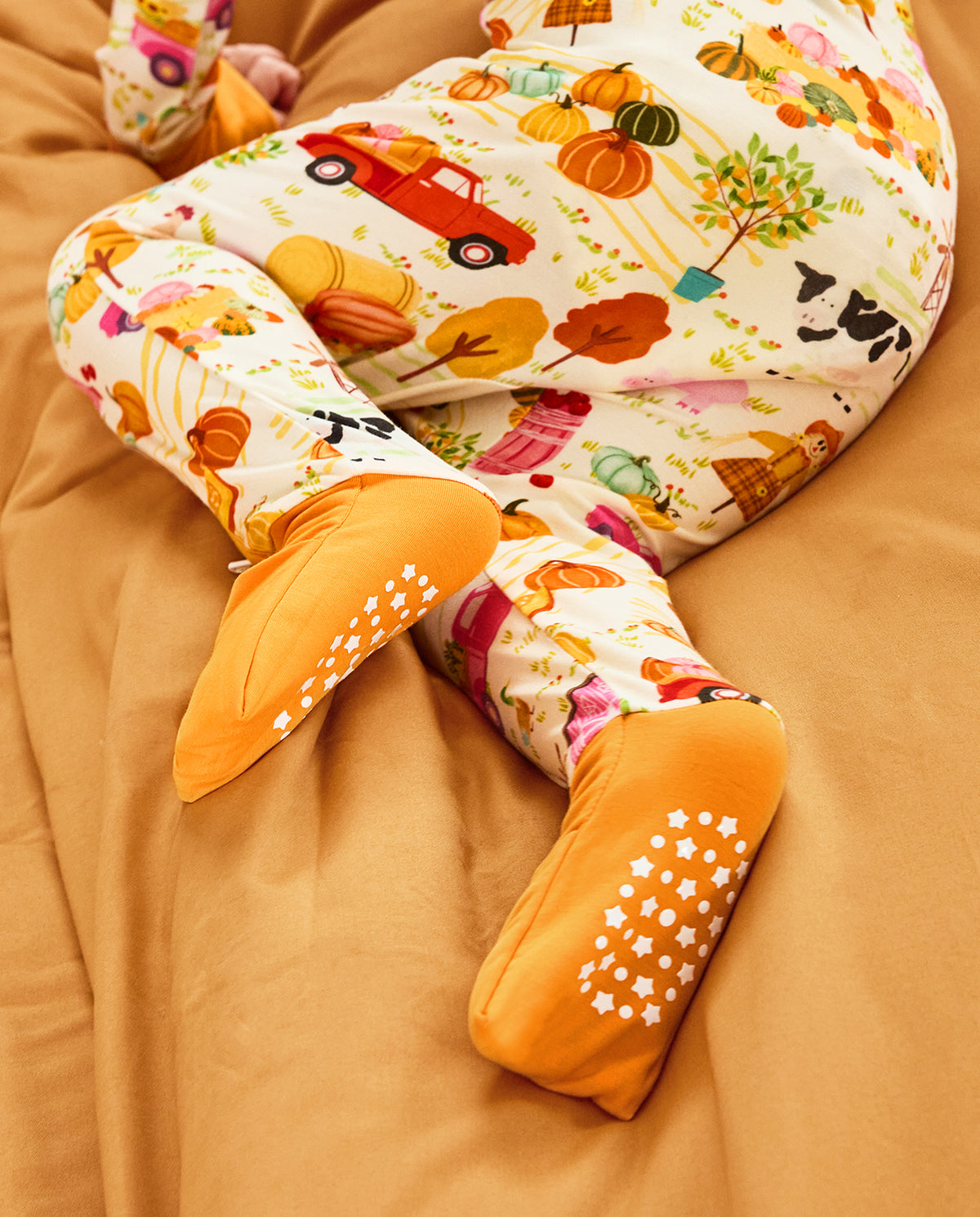 Close-up of orange foot cuffs and white sole grips on the Harvest Farm romper.