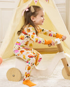 Side view of a child standing and holding a wooden rocker in the Harvest Farm romper.