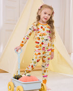 Smiling child holding a blue cart in Harvest Farm long-sleeve pajamas.