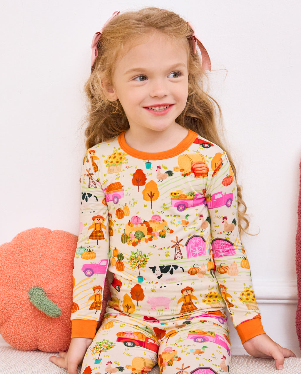 Front view of a child seated on a sofa in the Harvest Farm pajama set.