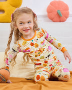 Side view of a child seated on a sofa wearing Harvest Farm pajamas.