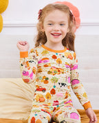 Child raising an arm while seated on a sofa in Harvest Farm pajamas.