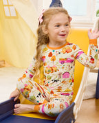 Closer view of a seated child with raised arms, showing Harvest Farm print and orange cuffs.