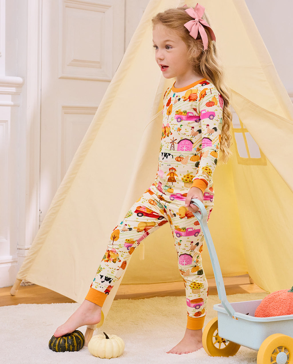 Side view of a child standing beside a cart in Harvest Farm pajamas.