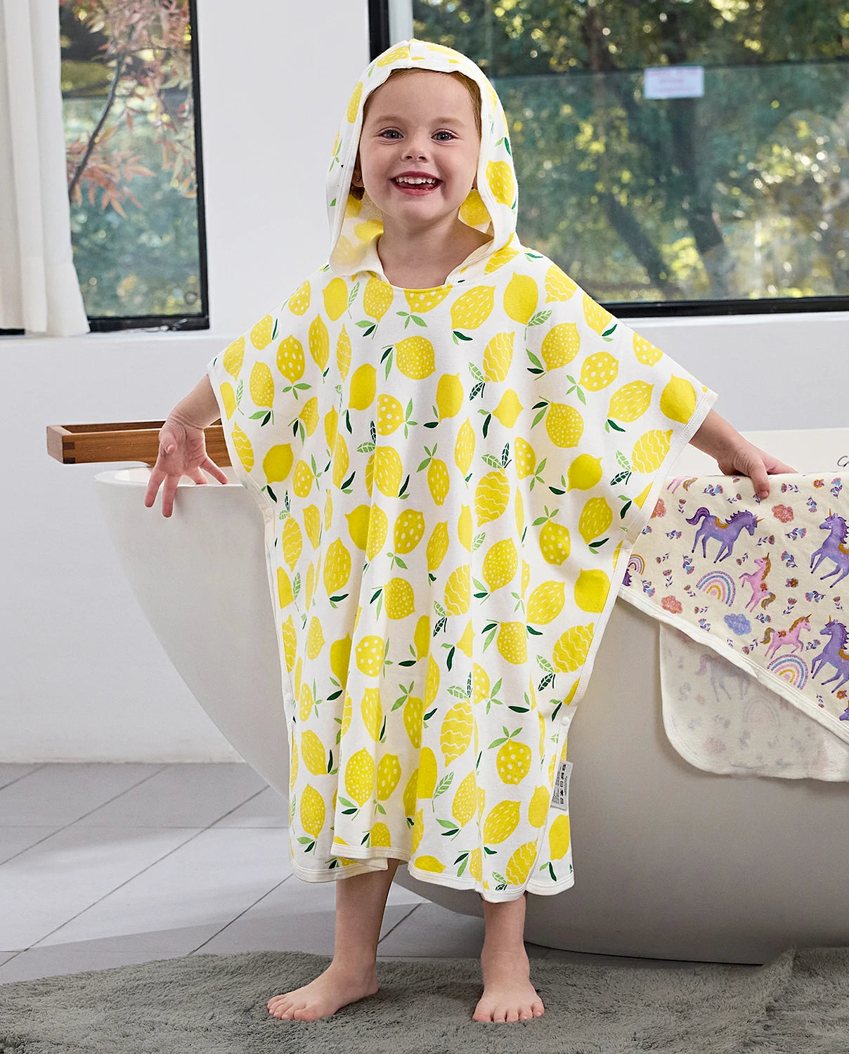 Lemon Tree Hooded Toddler Bath Towel - child wearing the lemon-print hooded towel in a bathroom, front view