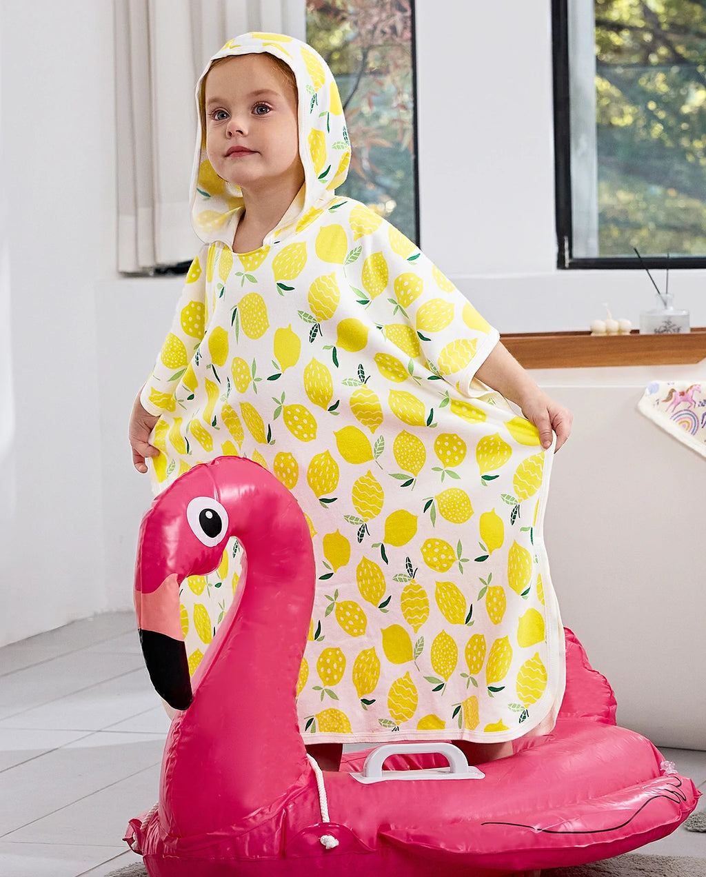 Lemon Tree Hooded Toddler Bath Towel - child wearing the hooded towel while seated on a flamingo pool float