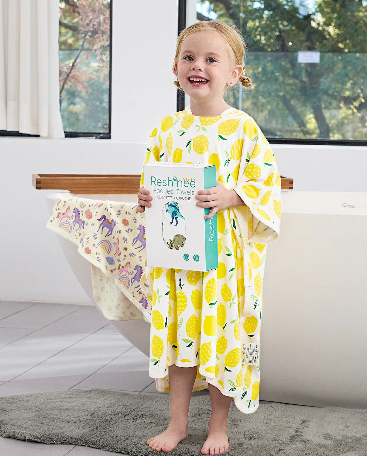 Lemon Tree Hooded Toddler Bath Towel - child wearing the hooded towel while holding the retail box