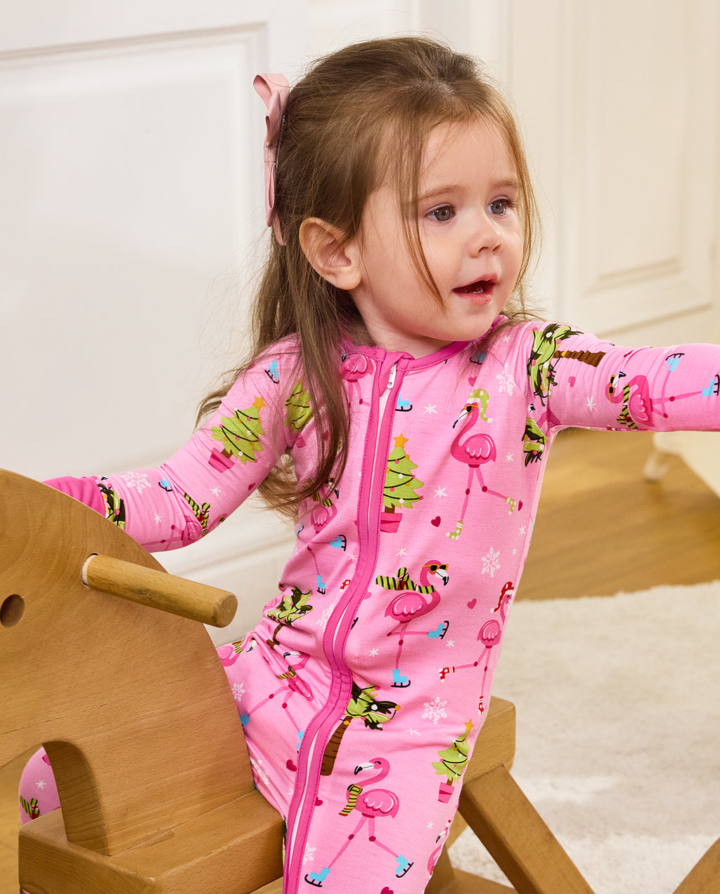 Child seated on a wooden rocking horse in the Merry Mingo romper.