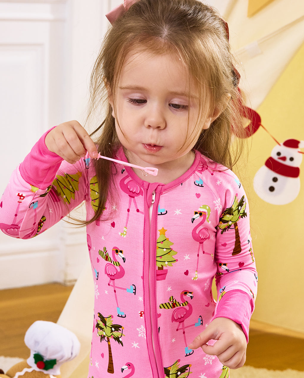 Close view of a child holding a small toy near the mouth in the Merry Mingo romper.