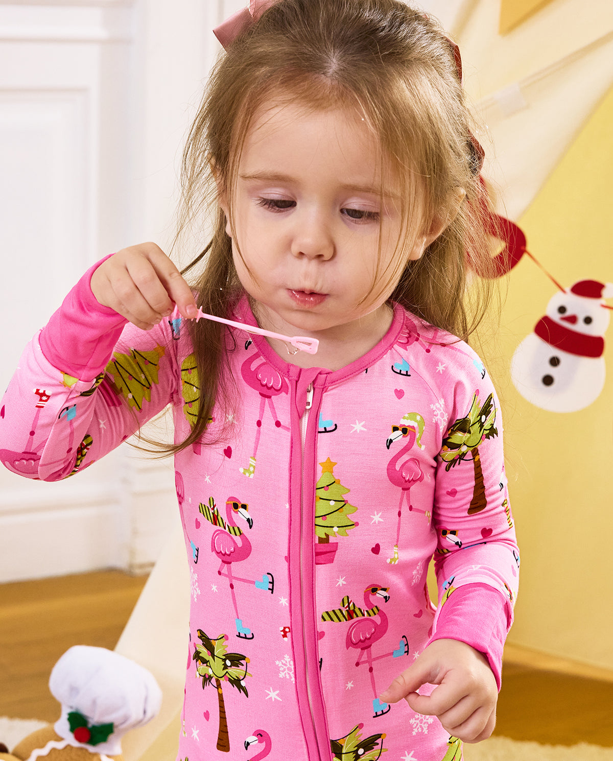 Close view of a child holding a small toy near the mouth in the Merry Mingo romper.