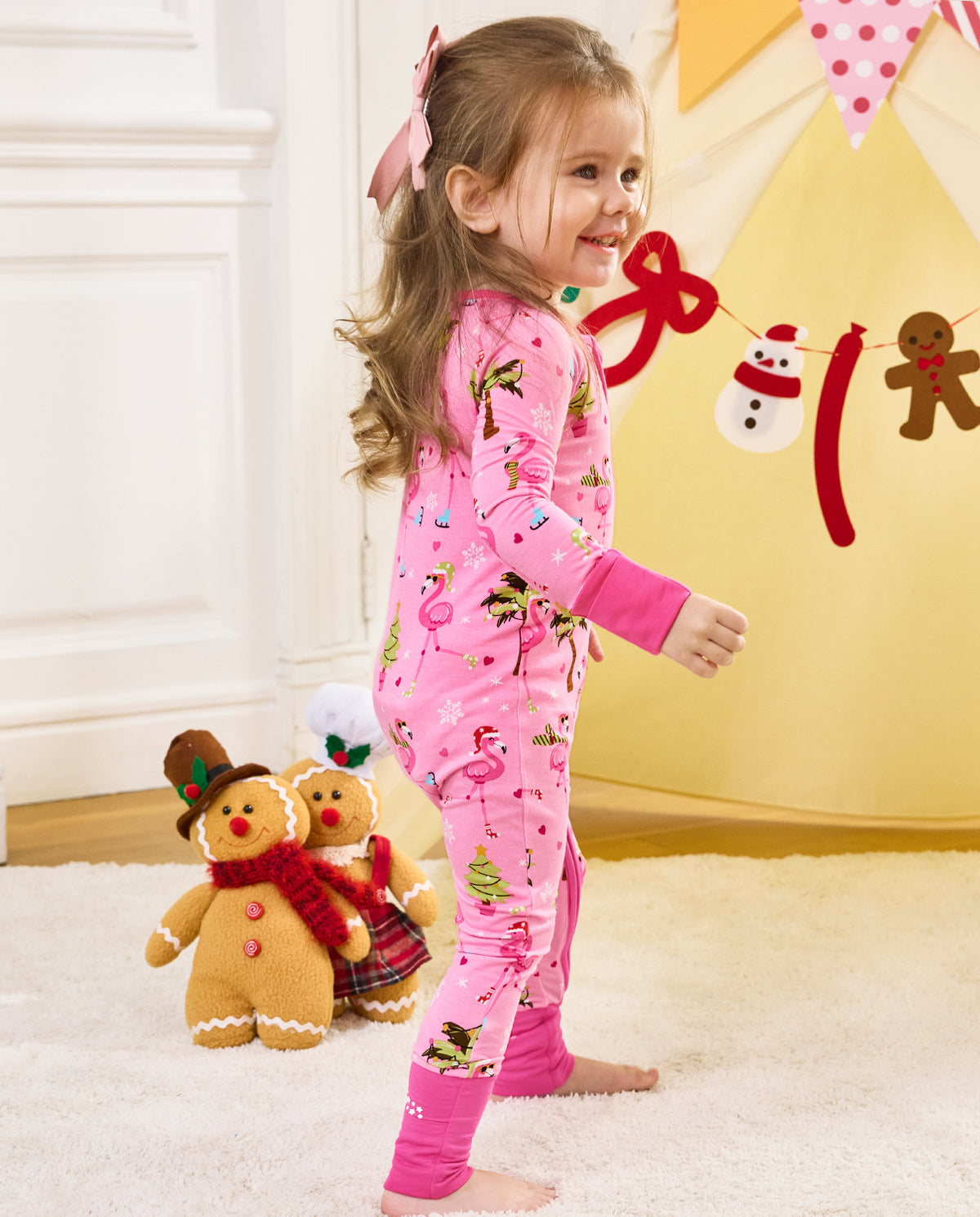 Side view of a child standing in the pink Merry Mingo romper.