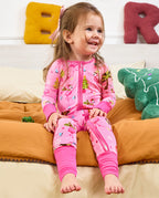 Child seated on orange bedding smiling in the Merry Mingo romper with uncovered feet.