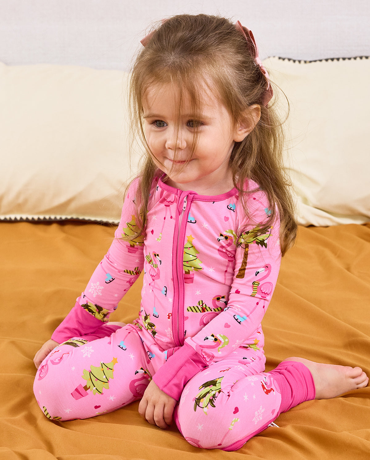 Child seated on bedding looking downward in the Merry Mingo romper.