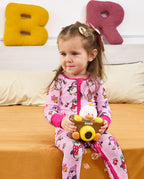 Child seated on orange bedding holding a toy camera in the Merry Penguins romper.