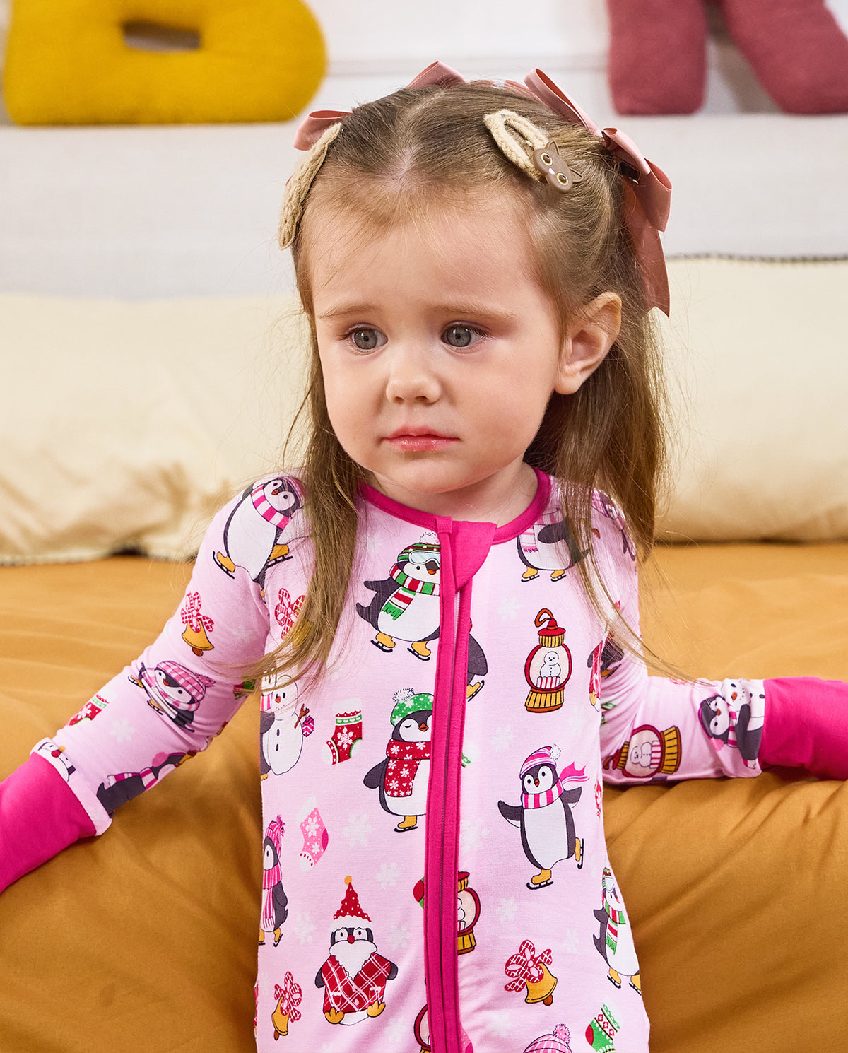 Close view of a child seated in the Merry Penguins romper with deep pink trim.