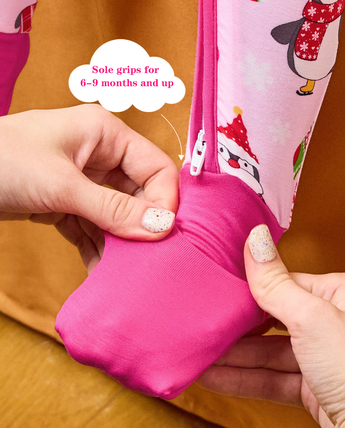Hands folding a deep pink foot cuff on the Merry Penguins romper, with the original annotation.