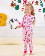Child standing on a sofa holding a penguin plush in Merry Penguins pajamas.