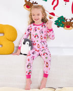 Child seated on a sofa with a penguin plush in Merry Penguins pajamas.