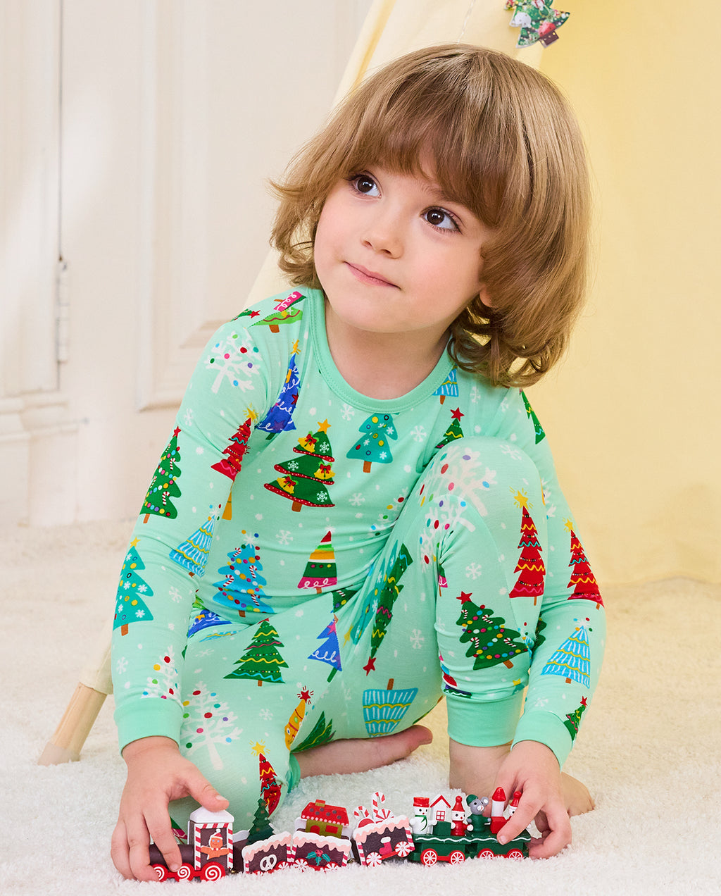 Child wearing Merry Trees mint-green two-piece pajamas while playing with toy trains