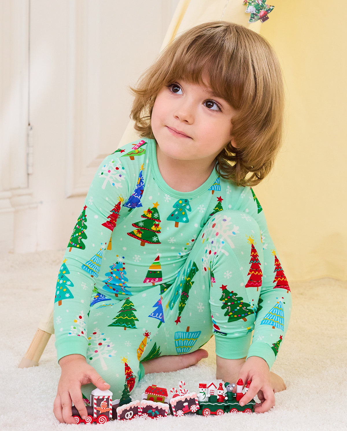 Child wearing Merry Trees mint-green two-piece pajamas while playing with toy trains
