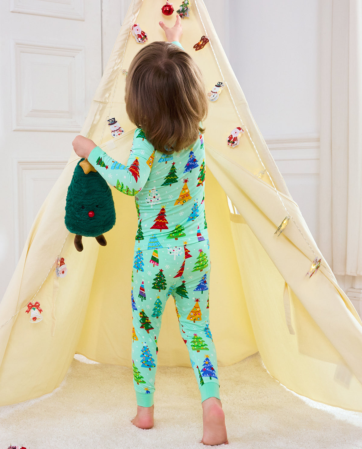 Rear view of Merry Trees long-sleeve pajamas beside a decorated holiday tent