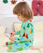 Child sitting on a sofa in Merry Trees pajamas while holding an open book