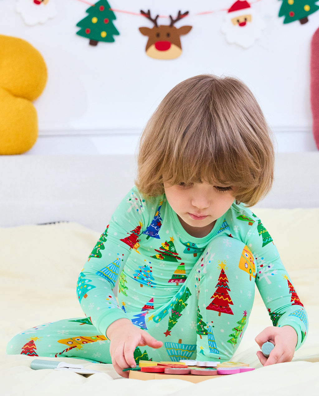 Child looking down while playing in Merry Trees Christmas-tree pajamas