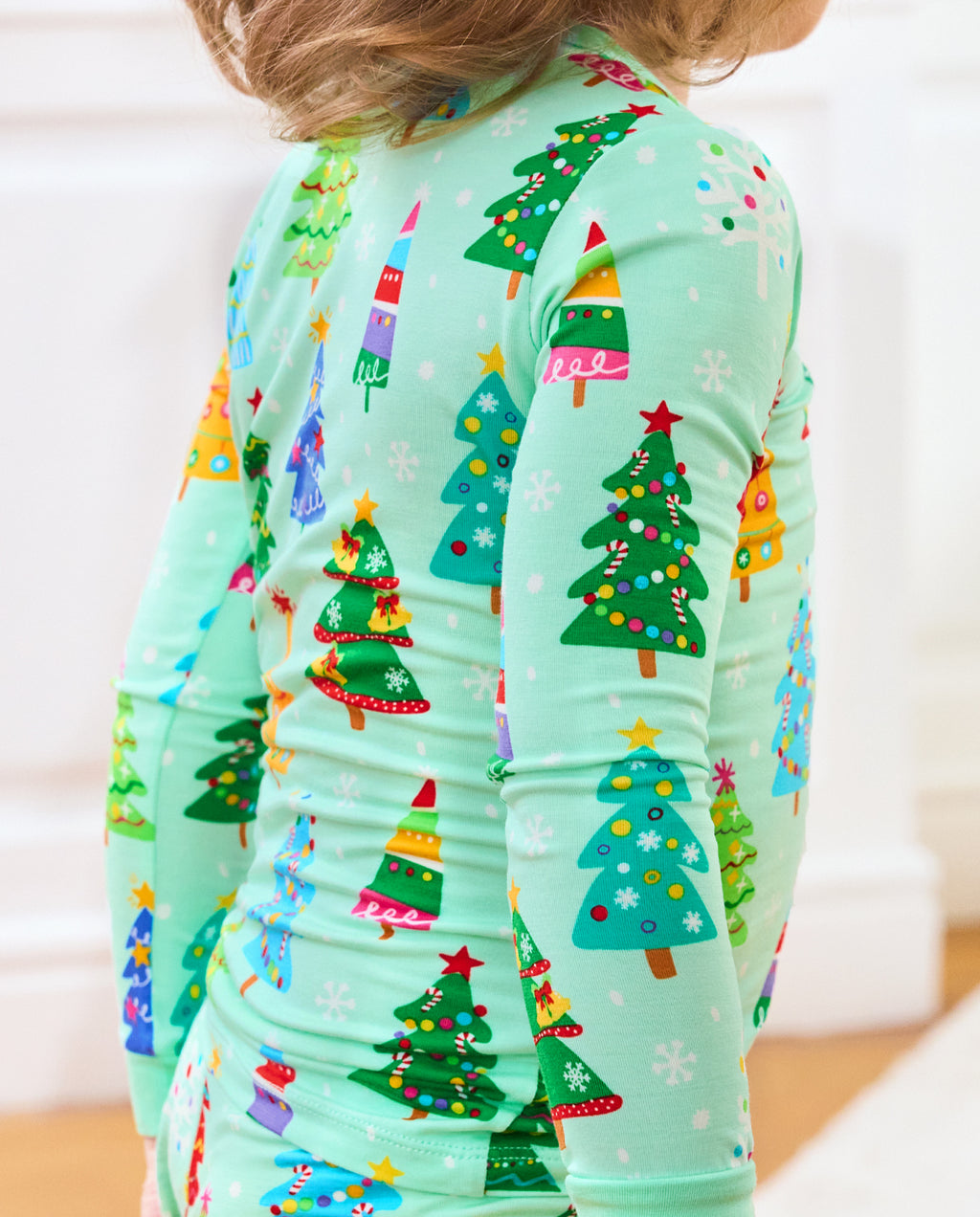 Close-up of Merry Trees mint-green pajama fabric and decorated Christmas-tree motifs