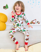Child sitting on a sofa in Merry Truckmas vehicle-print pajamas with red trim