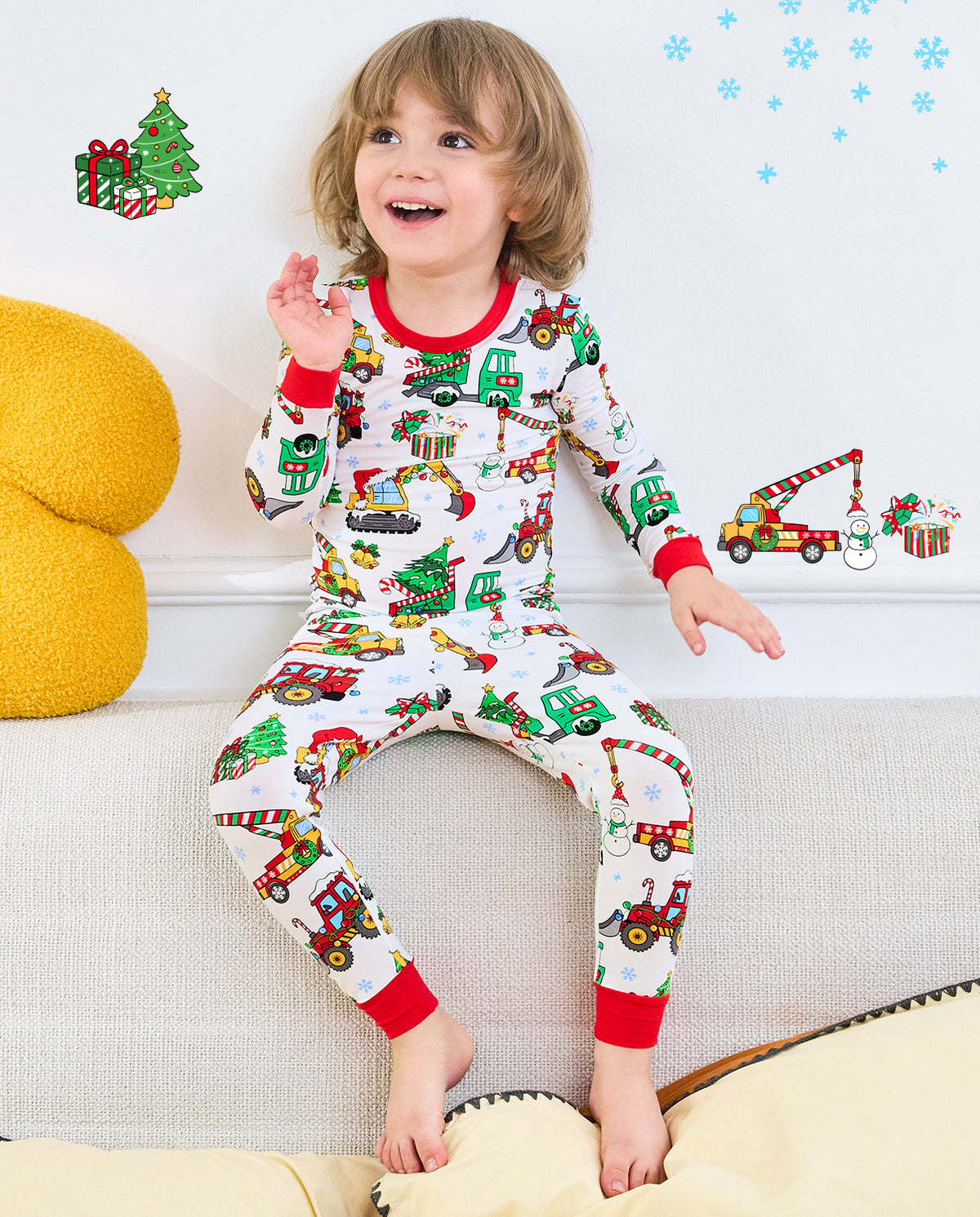 Child sitting on a sofa in Merry Truckmas vehicle-print pajamas with red trim