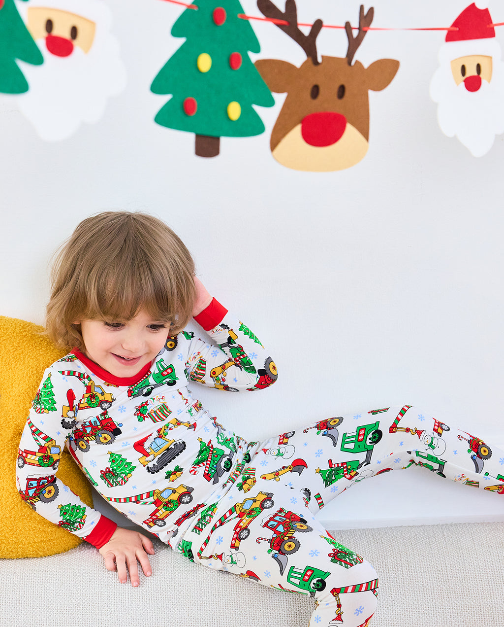 Child reclining on a sofa in Merry Truckmas pajamas beneath holiday decorations