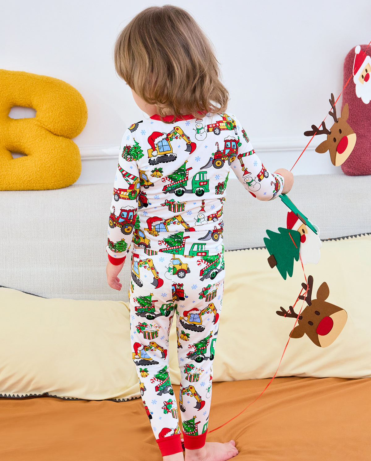 Child standing with back to camera in Merry Truckmas long-sleeve top and pants