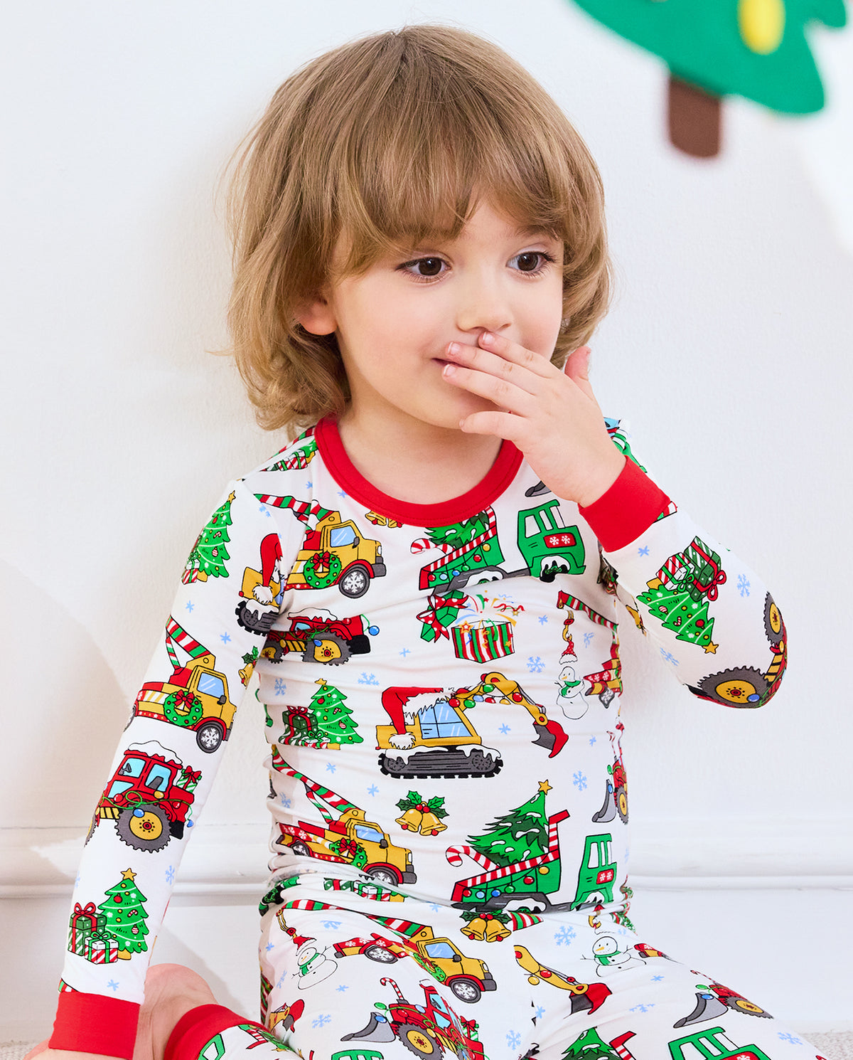 Close-up of Merry Truckmas top showing red collar, sleeve cuffs, trucks, and Christmas trees