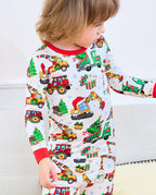 Child looking down at Merry Truckmas pajama top with decorated trucks and gifts