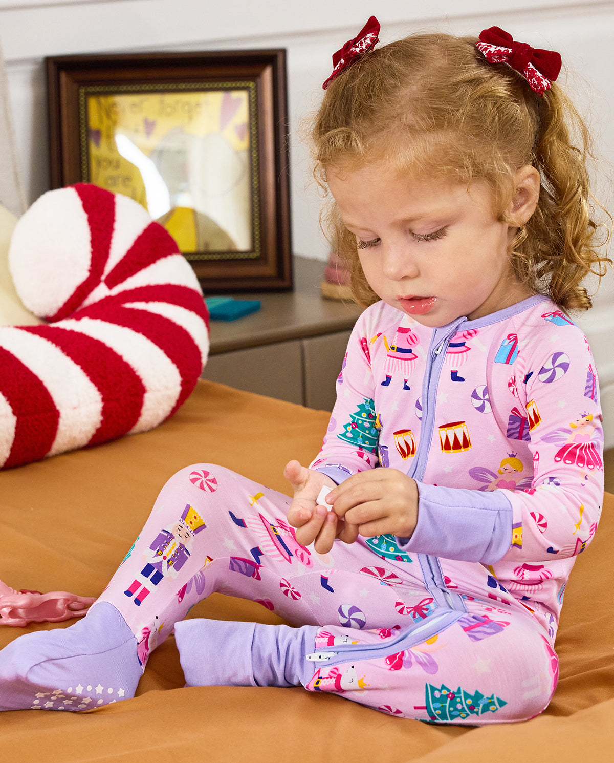 Child seated on a rug looking at a small object in the Nutcracker Fairy romper.