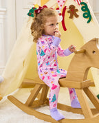 Child seated on a wooden rocking horse holding a small object in the Nutcracker Fairy romper.