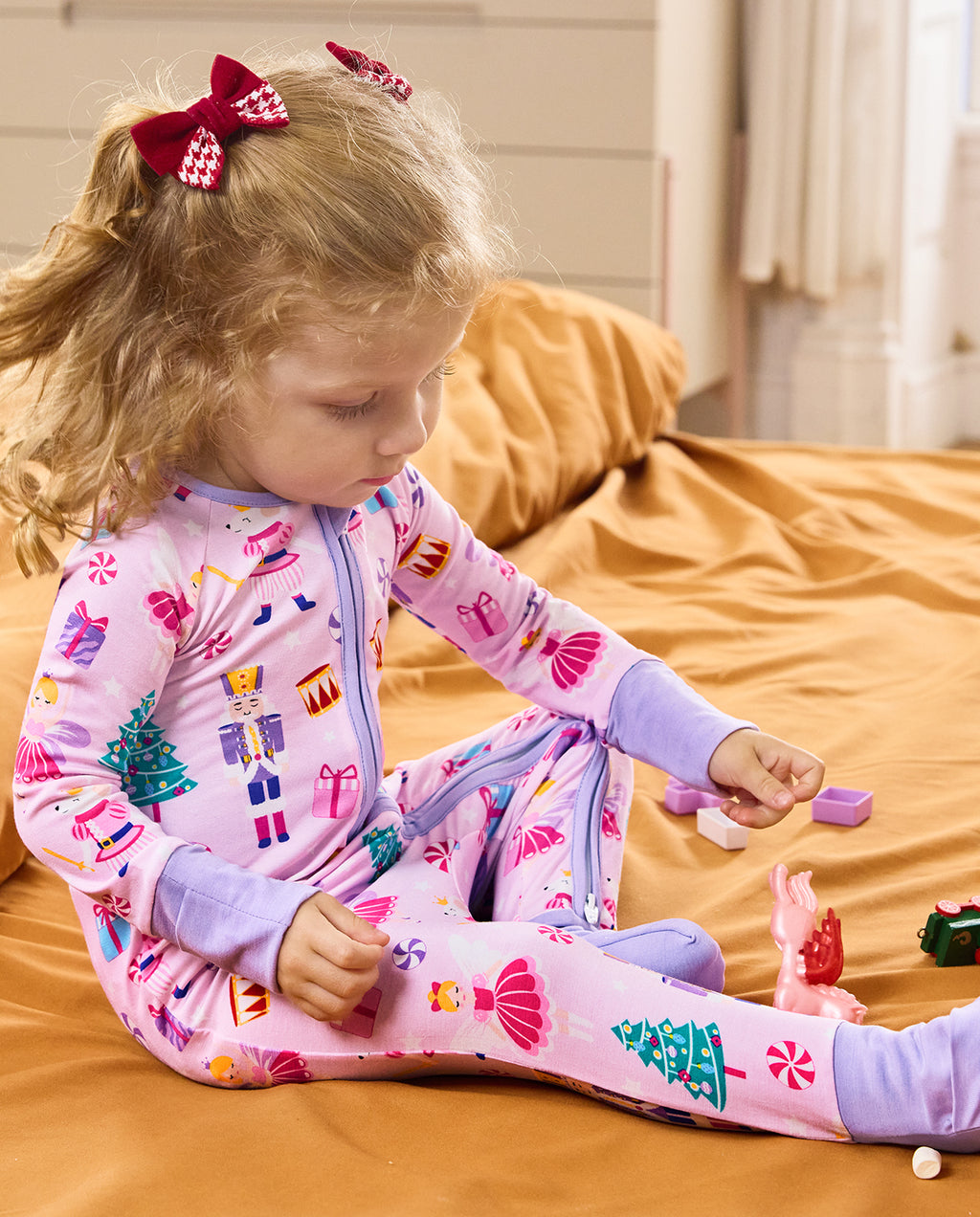 Child seated on a rug looking downward in the Nutcracker Fairy romper.