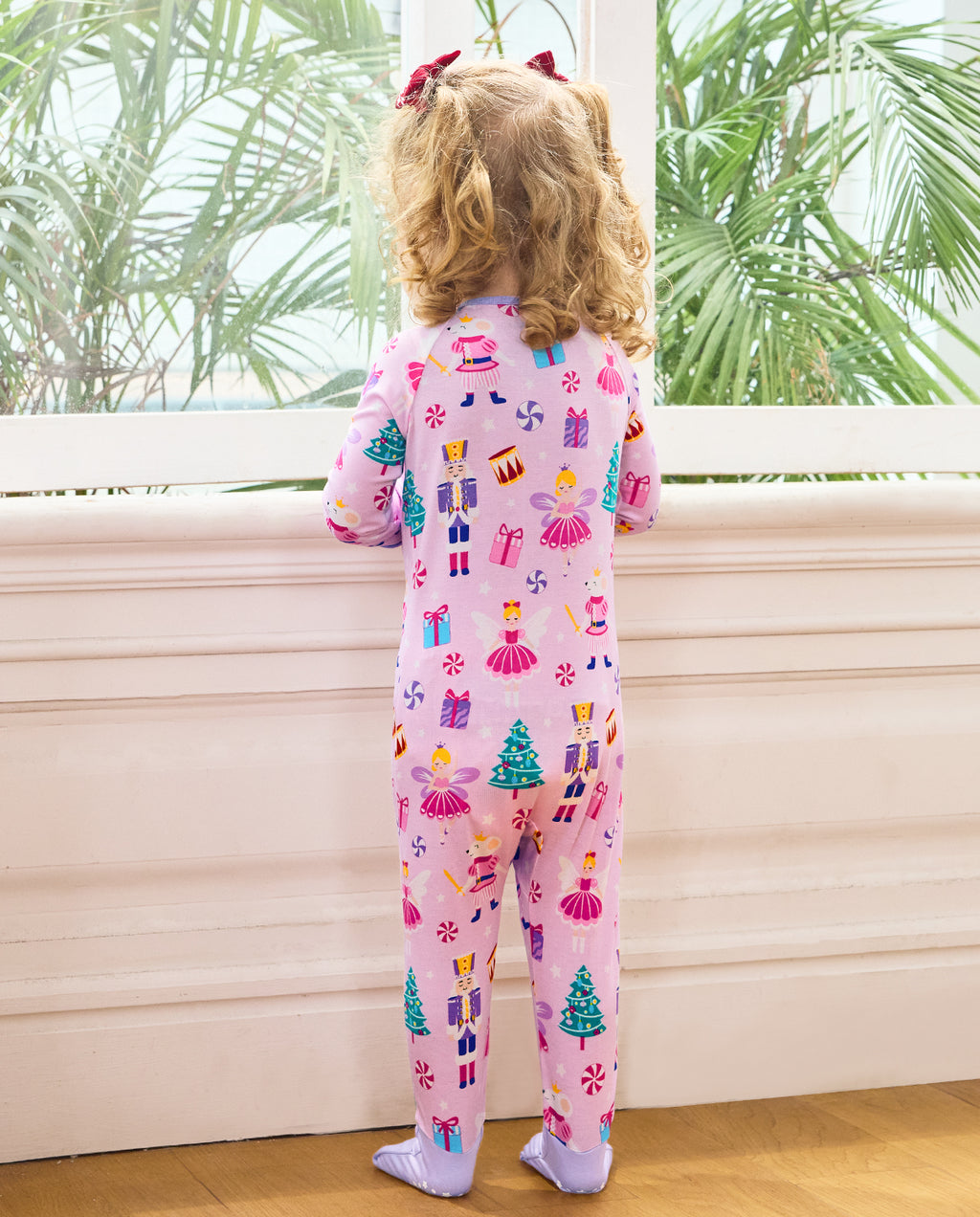 Rear view of a child standing beside a window in the Nutcracker Fairy romper.