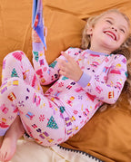 Child reclining on orange bedding and smiling in Nutcracker Fairy pajamas.