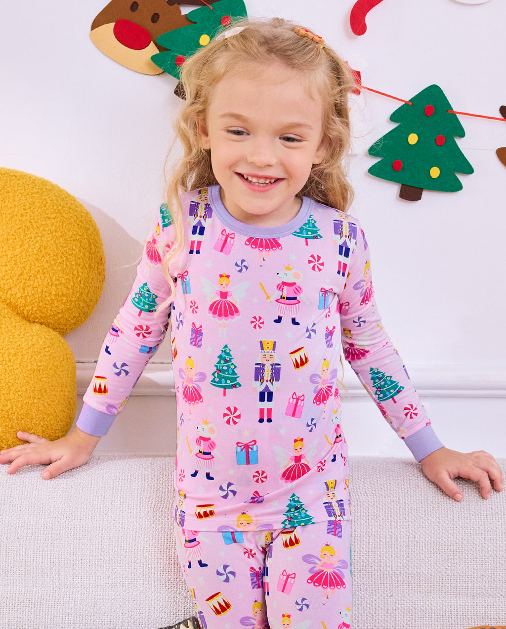 Child seated on a sofa with a wand in Nutcracker Fairy pajamas.