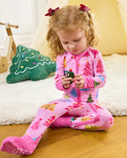 Child seated beside a wooden rocking horse holding a toy in the Pastel Christmas romper.
