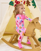 Child seated on a wooden rocking horse holding a toy in the Pastel Christmas romper.