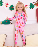 Child standing on a sofa with a plush tree in the pink Pastel Christmas pajama set.