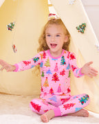 Child seated cross-legged by a holiday play tent in the Pastel Christmas pajama set.